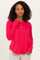 woman wearing a bright red long sleeve henley shirt with button details and a relaxed fit