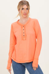 woman wearing an orange long sleeve henley top with button placket and a relaxed fit