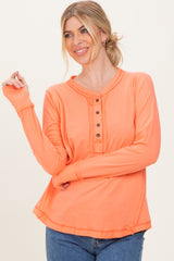 woman wearing an orange long sleeve henley t-shirt with button details and a relaxed fit