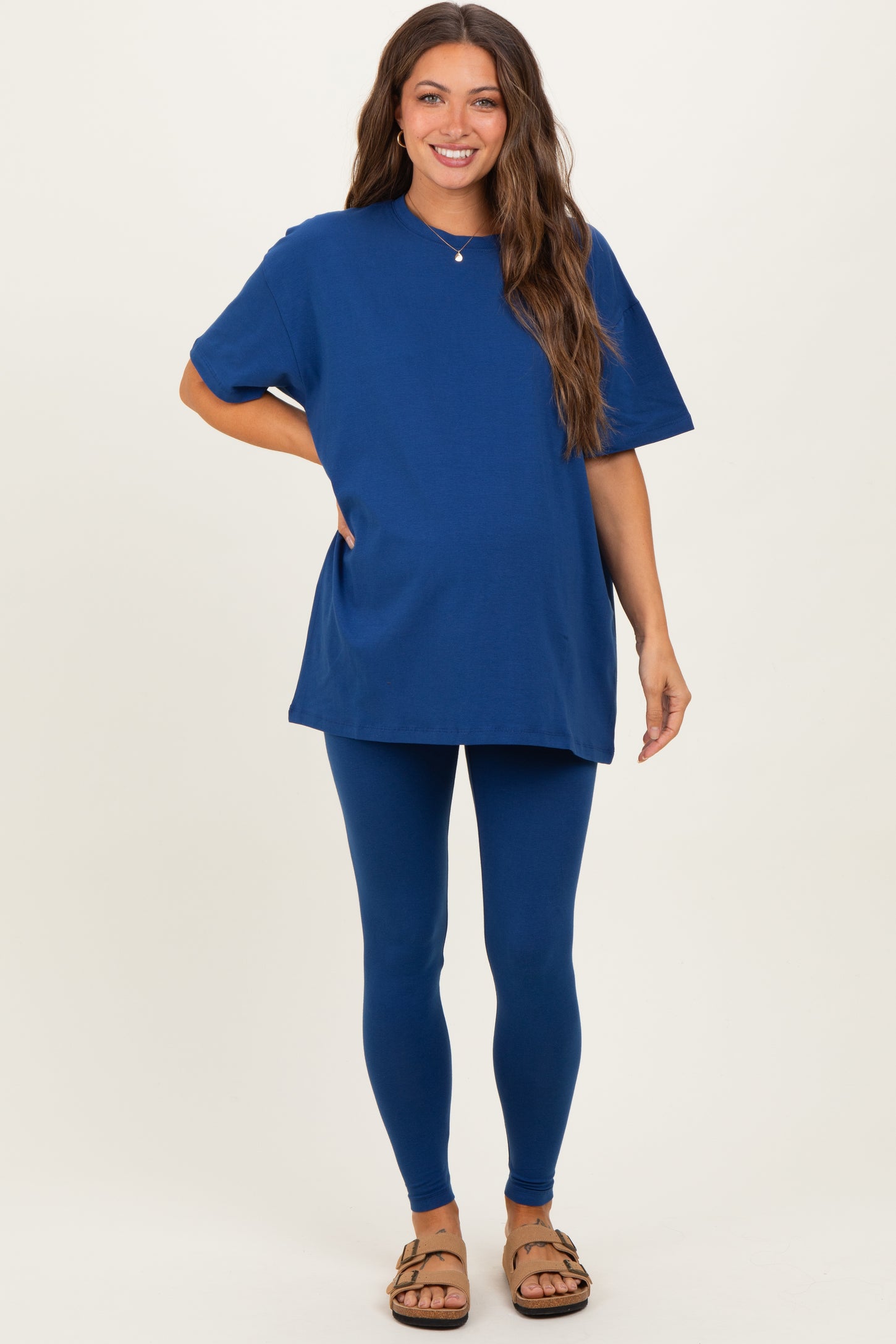 woman wearing a blue maternity t-shirt and matching leggings, with a visible baby bump