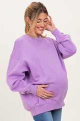 woman wearing a lavender oversized maternity sweatshirt and holding her baby bump