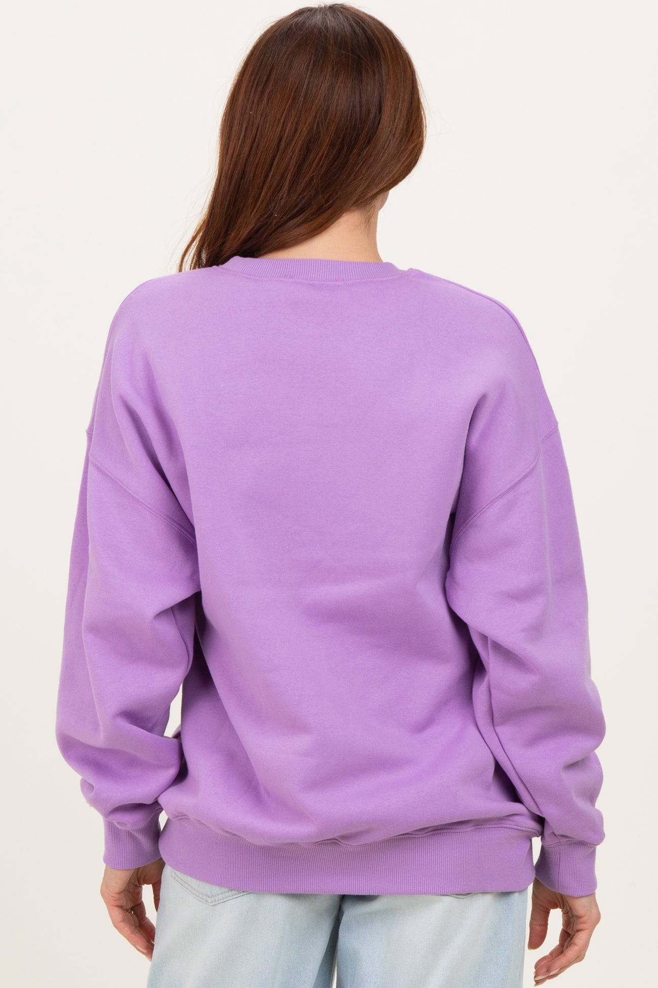 woman wearing a lilac oversized sweatshirt seen from the back with dropped shoulders and ribbed cuffs