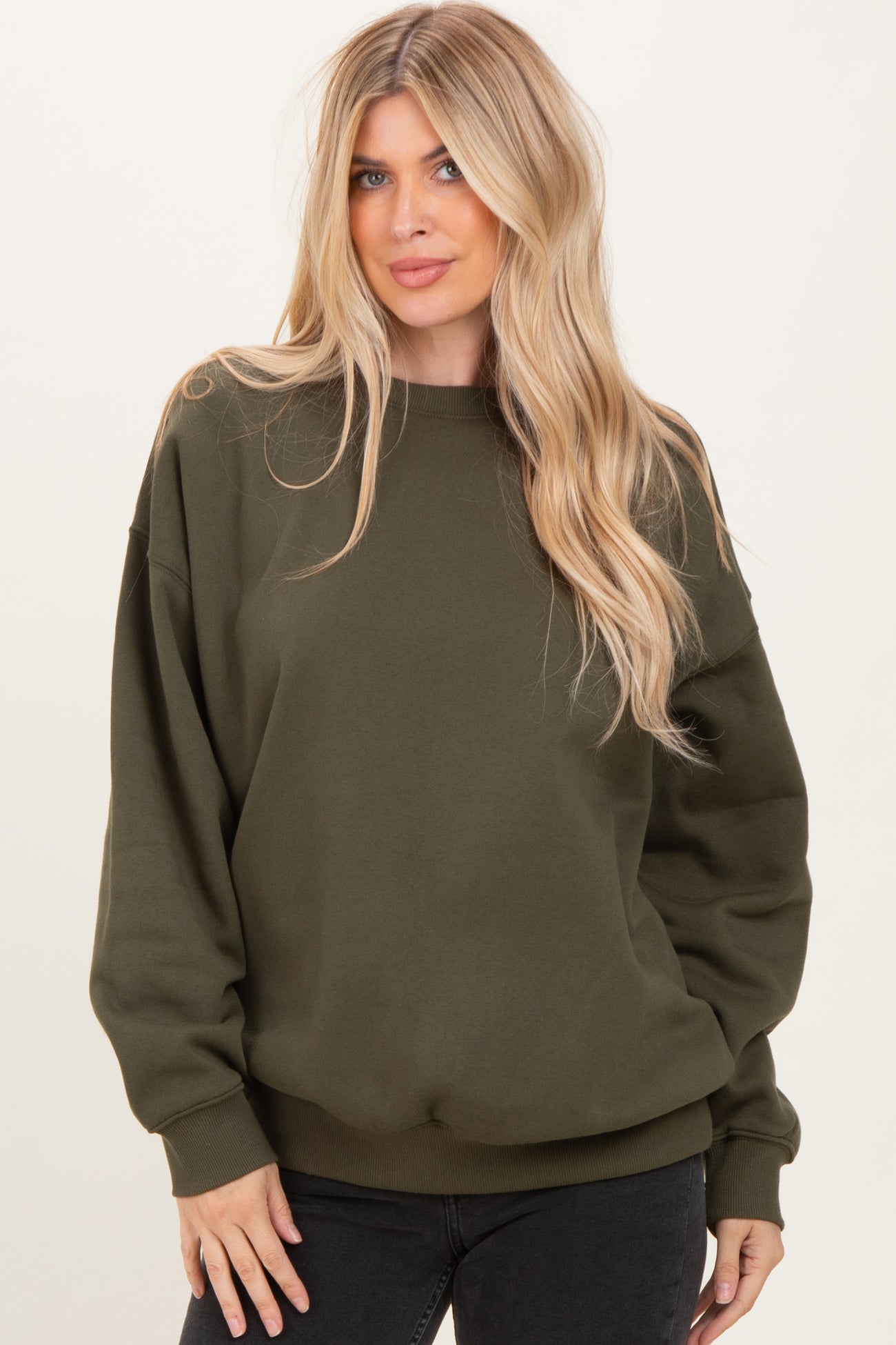 woman wearing an olive green oversized sweatshirt with dropped shoulders and a relaxed fit