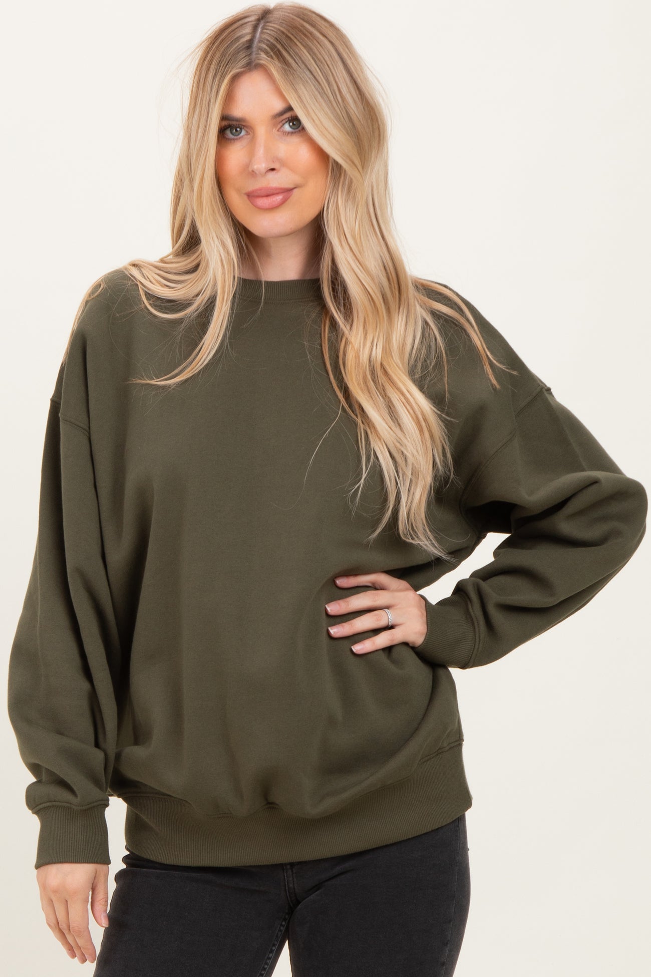 woman wearing an olive green oversized sweatshirt with a relaxed fit and long sleeves