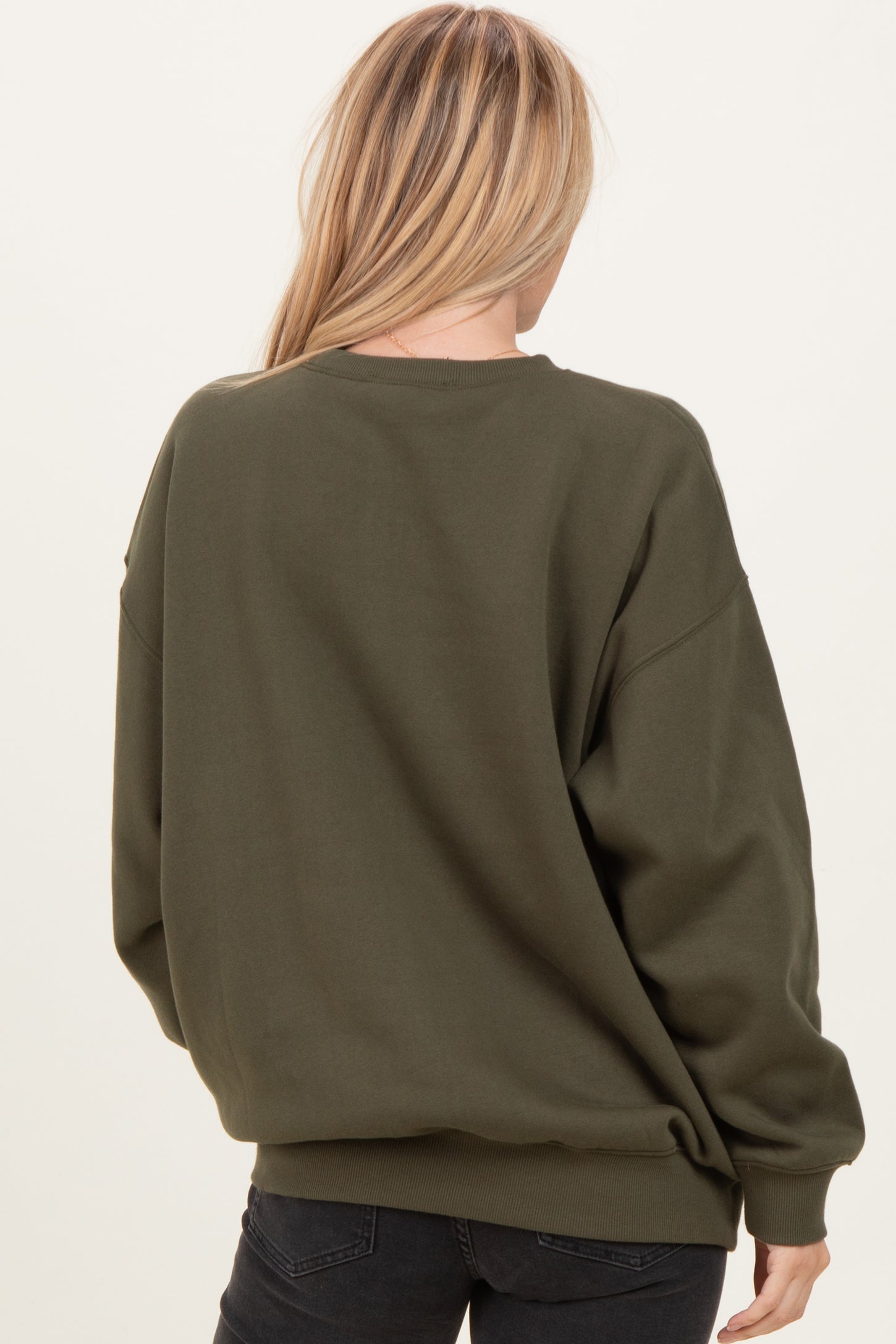 woman wearing an olive green oversized sweatshirt, viewed from the back