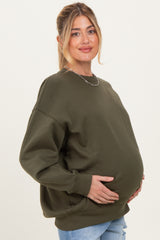 woman wearing an olive green oversized maternity sweatshirt and holding her baby bump