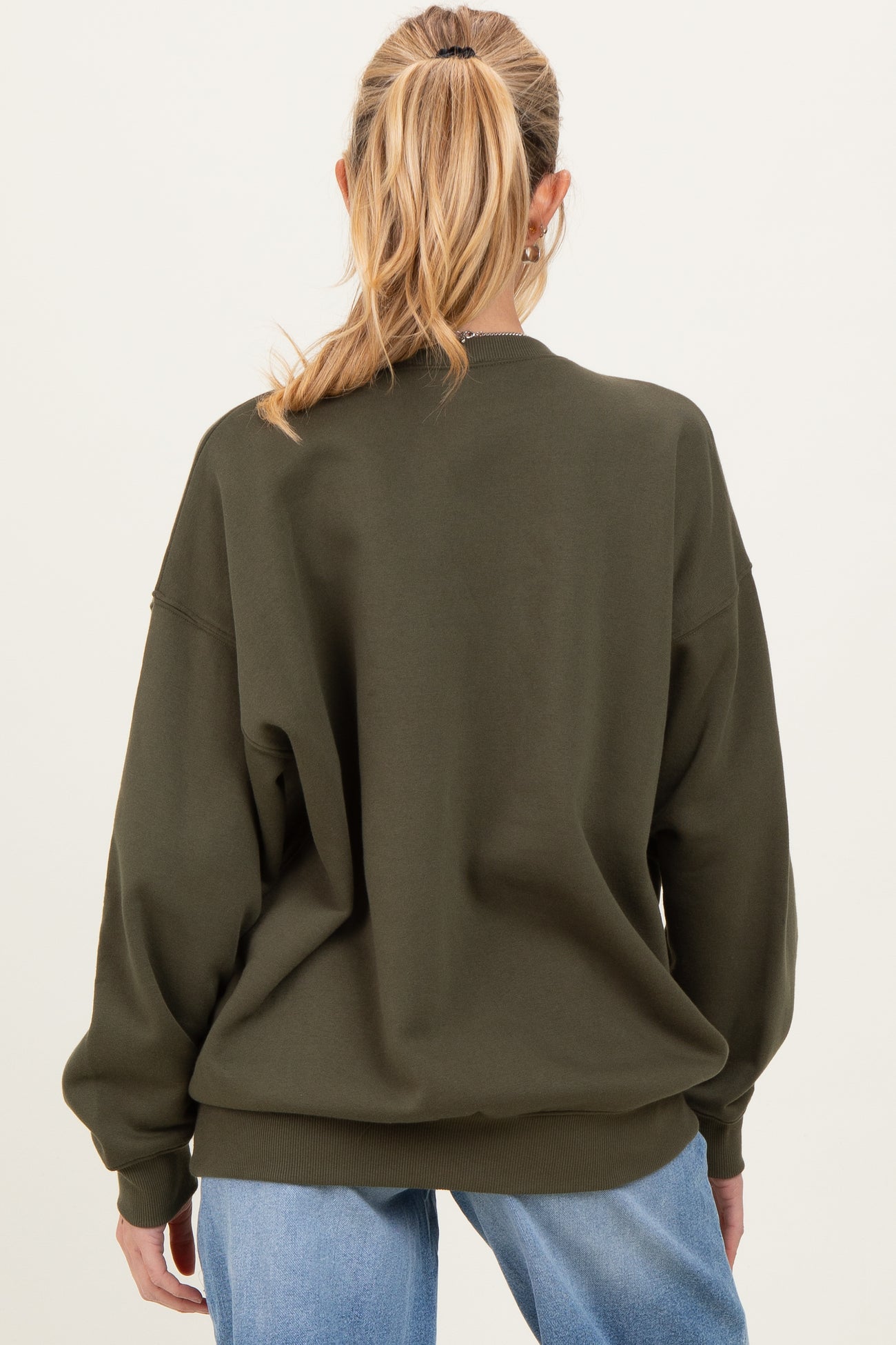 woman wearing an olive green oversized maternity sweatshirt, seen from the back