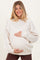 woman wearing a cream oversized maternity sweatshirt and holding her baby bump