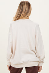 woman wearing a beige oversized maternity sweatshirt, viewed from the back