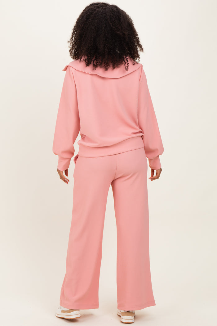 woman wearing a pink ribbed loungewear set with a hoodie and wide-leg pants, shown from the back