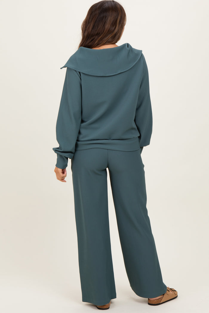 woman wearing a teal maternity loungewear set with a wide collar top and matching pants, showcasing a relaxed fit.
