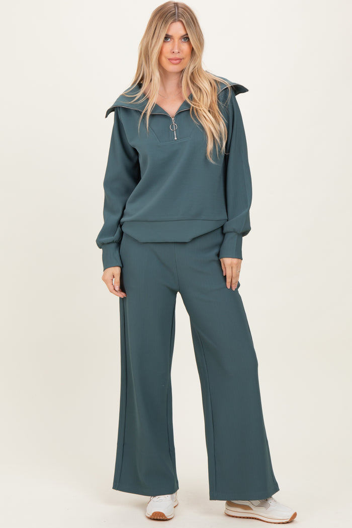 woman wearing a teal ribbed pullover with zip and matching wide-leg pants, styled with white sneakers