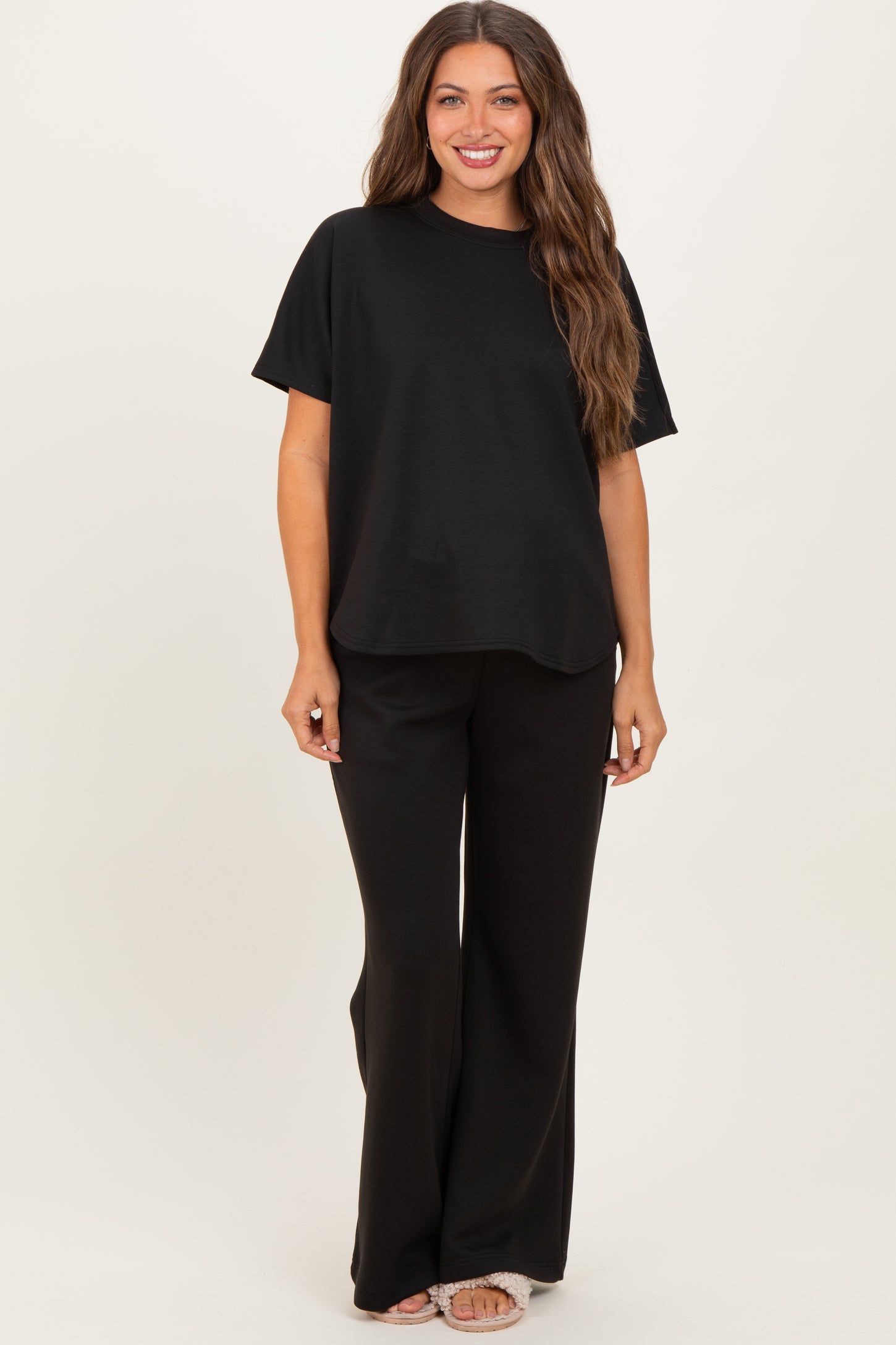 woman wearing a black short sleeve maternity top and matching black wide-leg maternity pants