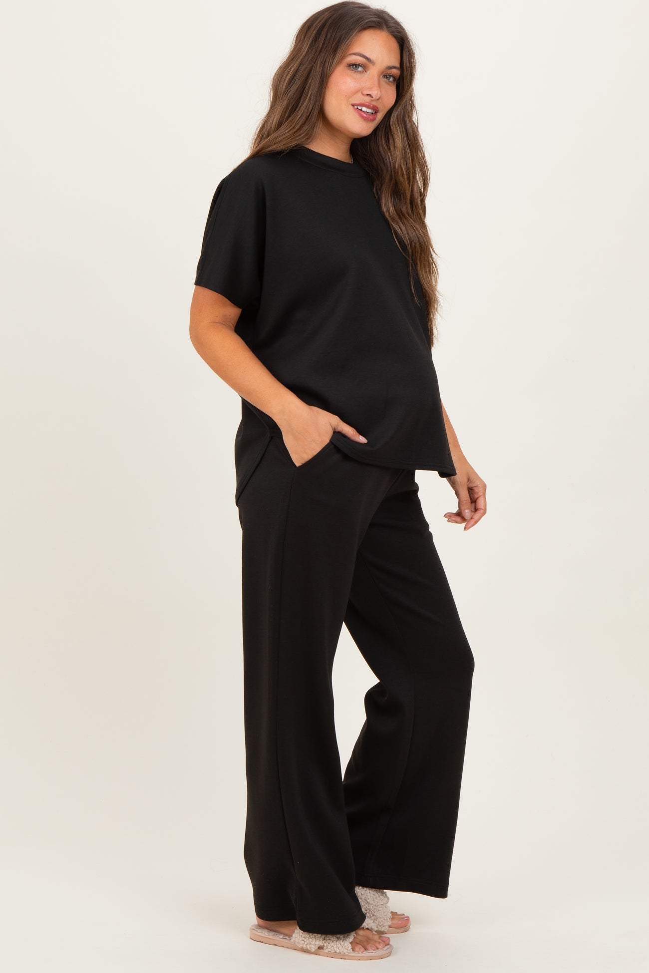 woman wearing a black maternity top and black wide-leg pants with side pockets, displaying a baby bump