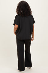 woman wearing a black short sleeve top and matching wide-leg pants, viewed from the back