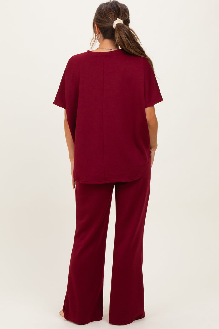 woman wearing a burgundy maternity top and matching flared pants, showing the back view of the outfit