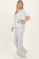 woman wearing a gray two-piece lounge set with a relaxed fit top and matching pants, paired with white sneakers