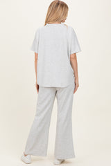 woman wearing a gray matching set with a short sleeve top and wide-leg pants, standing with her back to the camera