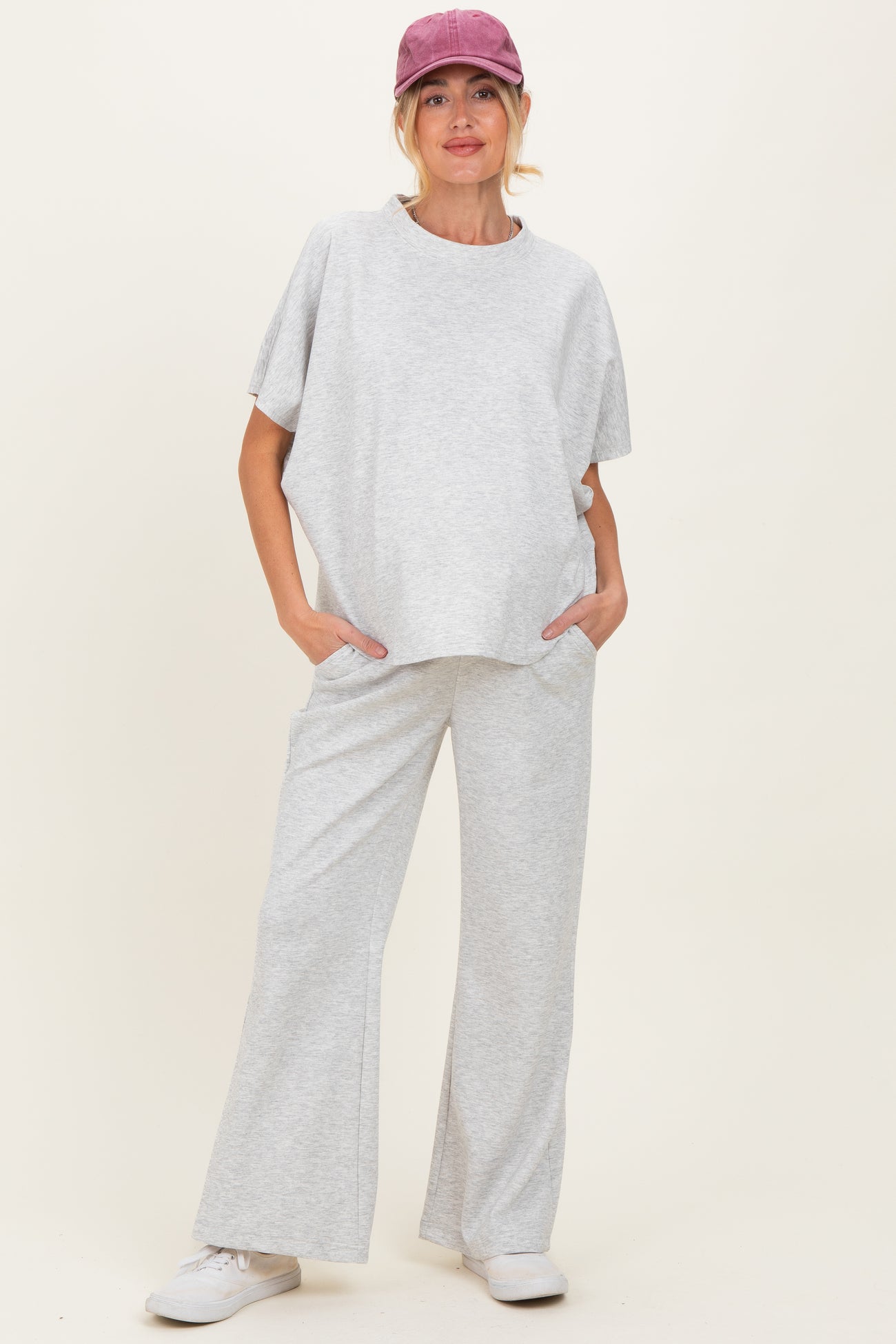 woman wearing a gray maternity lounge set with a relaxed top and wide-leg pants, casually posing with hands in pockets
