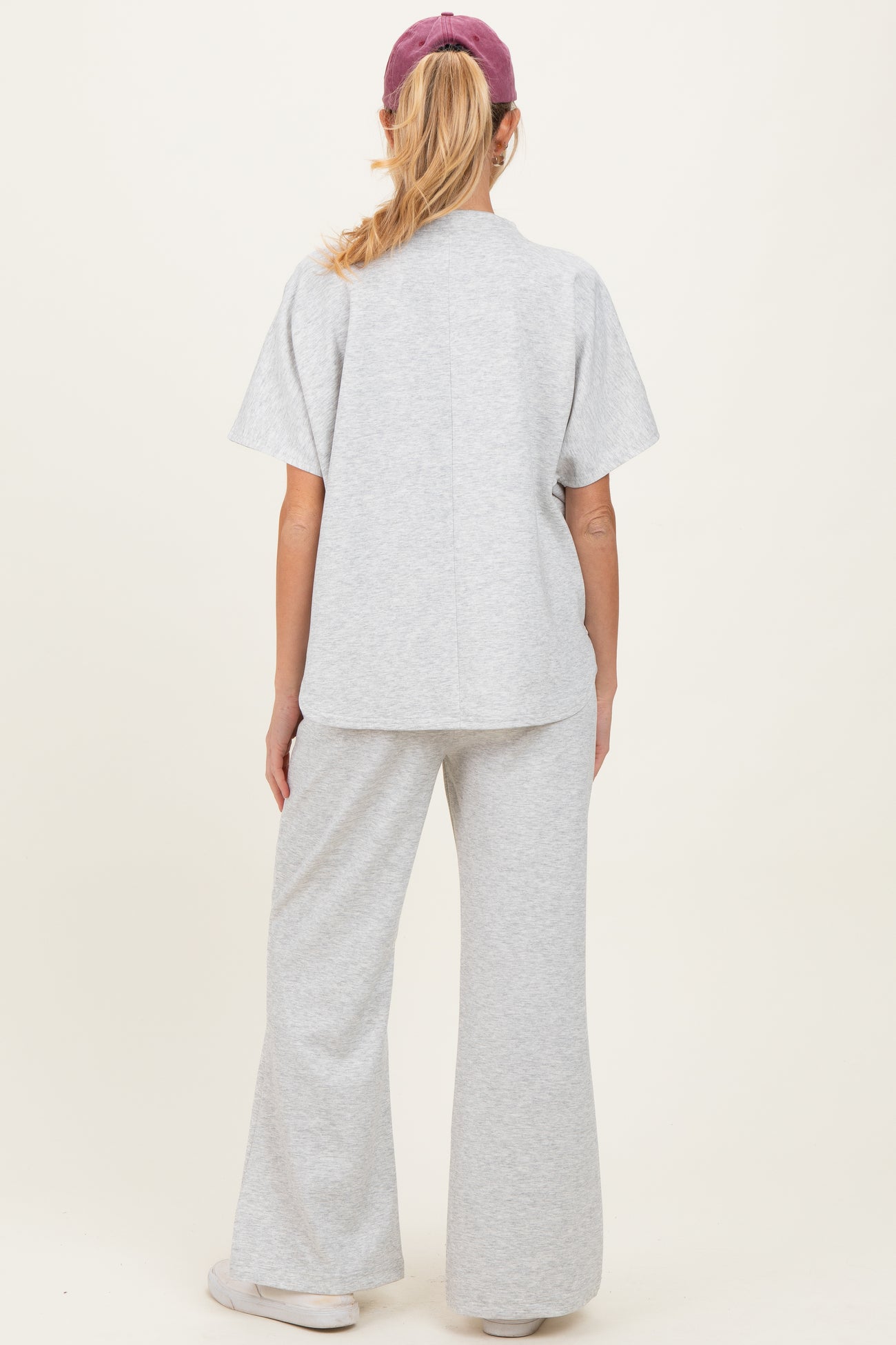 woman wearing a gray maternity sweatshirt and matching flared pants, showing the back view