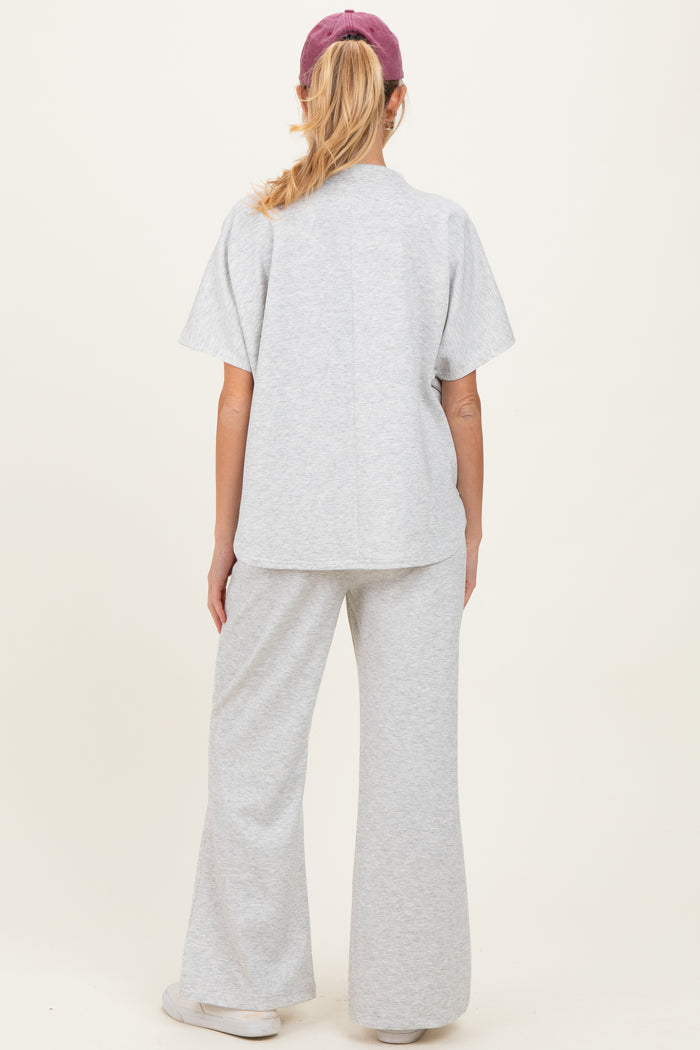 woman wearing a gray maternity sweatshirt and matching flared pants, showing the back view