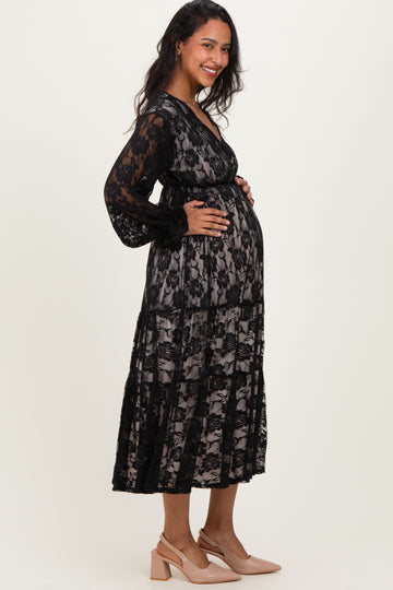 woman wearing a black lace maternity dress with a sheer overlay and a visible baby bump