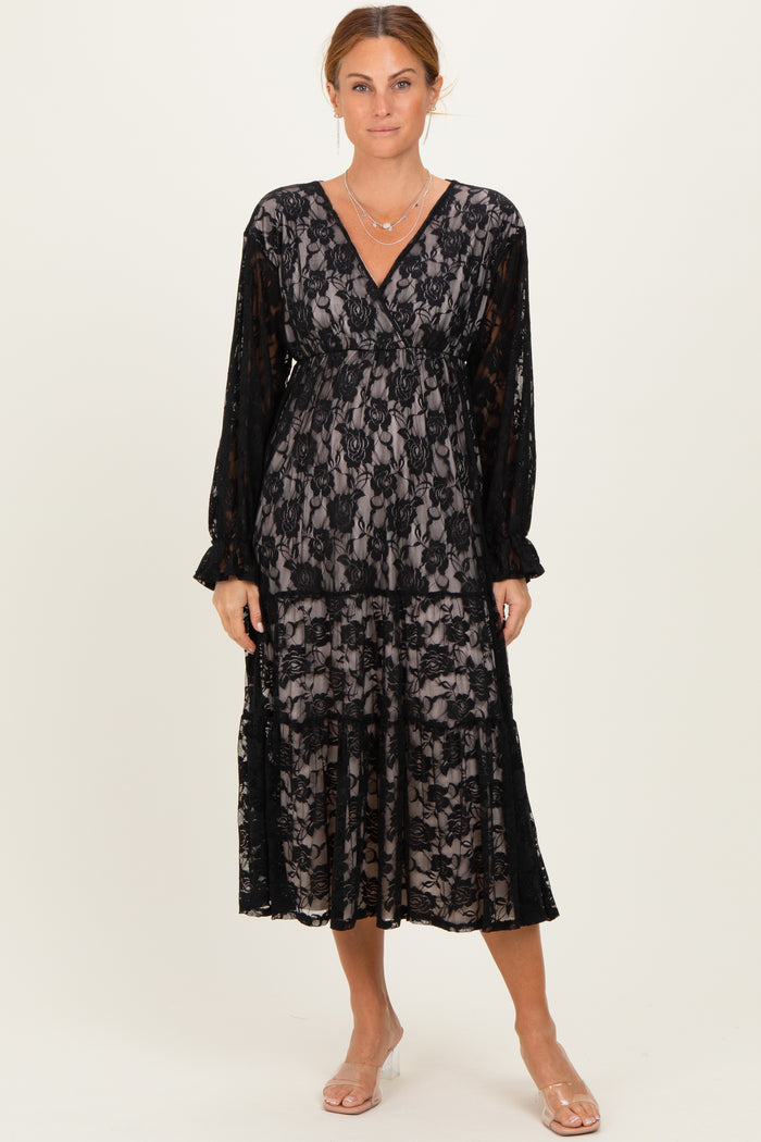 woman wearing a black lace long sleeve wrap dress with a tiered skirt and a v-neckline