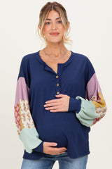 woman wearing a navy maternity top with colorful patterned sleeves and holding her baby bump