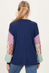 woman wearing a navy blue ribbed maternity top with patterned long sleeves and relaxed fit from the back