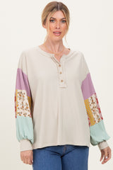 woman wearing a beige ribbed blouse with colorful patterned sleeves and button details