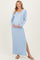 woman wearing a light blue ribbed maternity maxi dress with long sleeves and a side slit, showing her baby bump