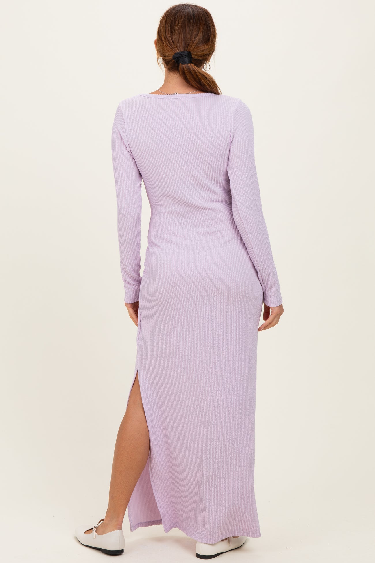 woman wearing a lilac long sleeve ribbed maxi dress with a side slit, viewed from the back