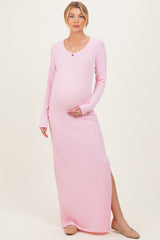 woman wearing a light pink long sleeve maternity dress with a side slit and holding her baby bump