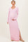 woman wearing a light pink long sleeve maternity dress with a side slit and holding her baby bump