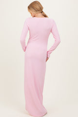 woman wearing a long pink ribbed maternity dress, showing the back view and a fitted silhouette