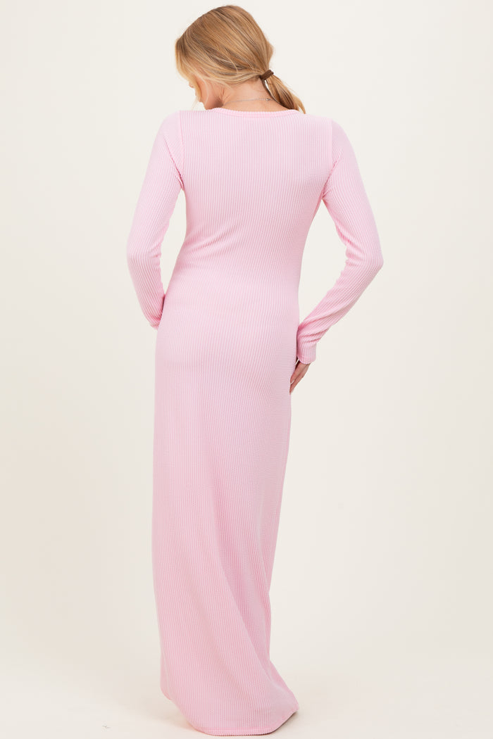 woman wearing a long pink ribbed maternity dress, showing the back view and a fitted silhouette