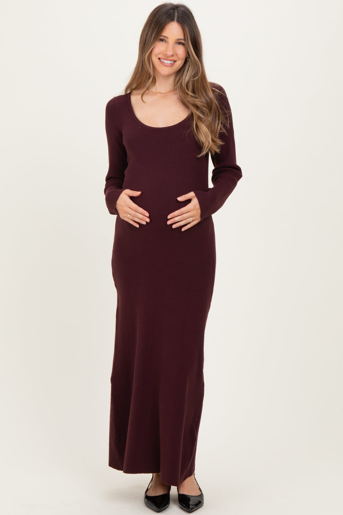 woman wearing a burgundy long sleeve ribbed maternity dress and holding her baby bump