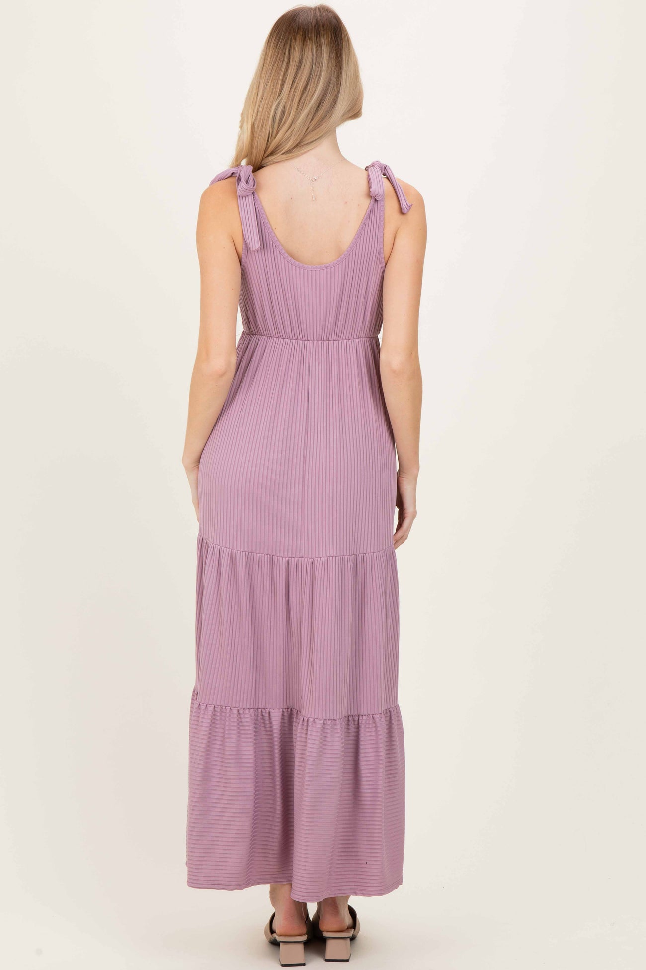 woman wearing a lavender striped maxi dress with tie shoulder straps and a tiered skirt, viewed from the back