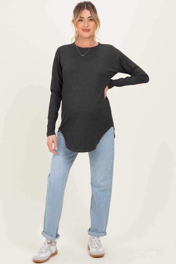 woman wearing a dark gray maternity long sleeve top and light blue jeans, showing her baby bump