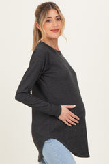 woman wearing a charcoal gray long sleeve maternity top and holding her baby bump