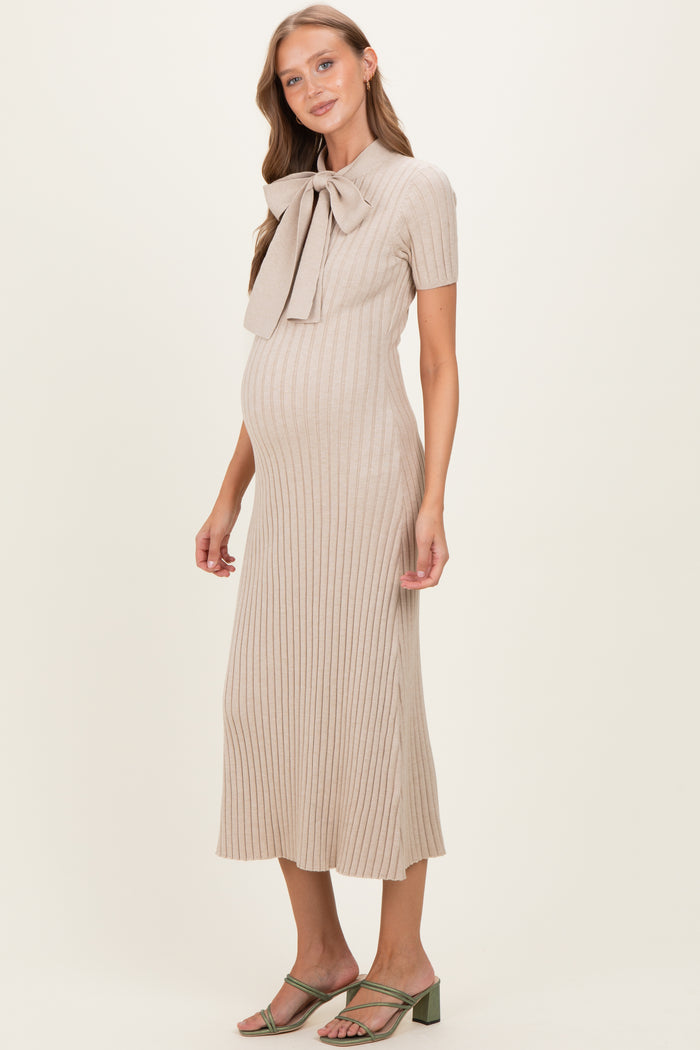 woman wearing a beige ribbed maternity dress with a bow collar and a visible baby bump