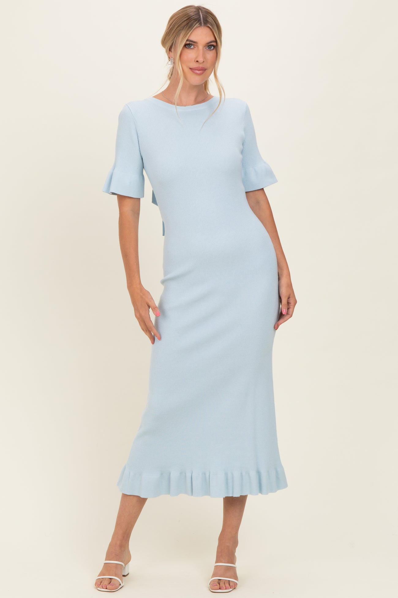 woman wearing a light blue ribbed midi dress with fluted sleeves and a ruffled hem