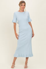 woman wearing a light blue ribbed midi dress with fluted sleeves and a ruffled hem