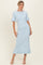 woman wearing a light blue ribbed midi dress with fluted sleeves and a ruffled hem