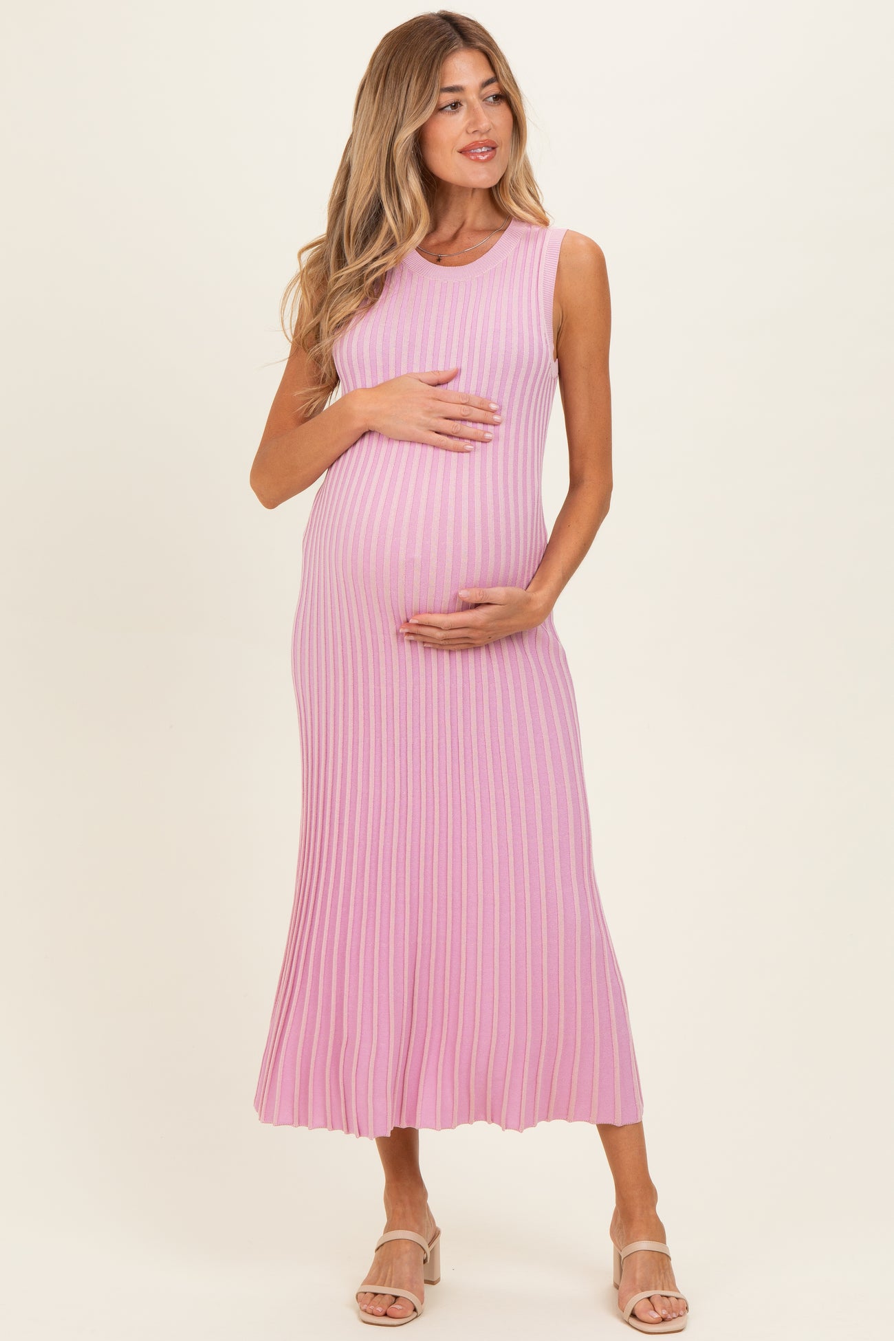 woman wearing a pink ribbed maternity dress and holding her baby bump