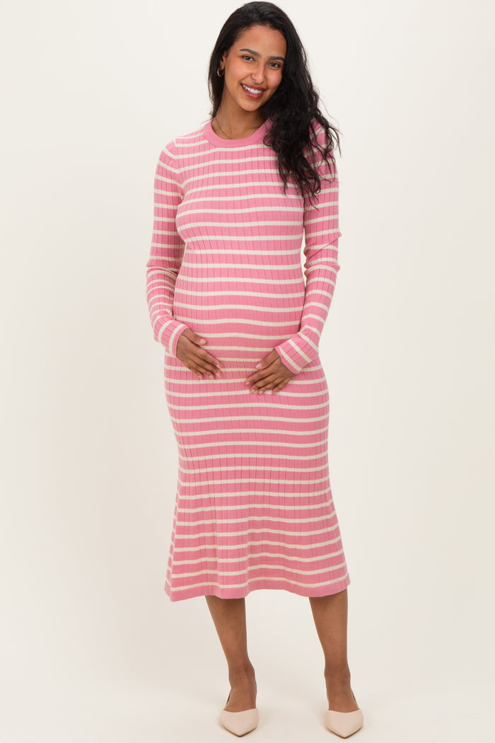woman wearing a pink striped long sleeve maternity dress and gently holding her baby bump