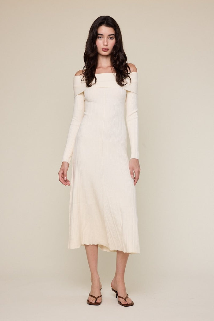woman wearing a creamy off-the-shoulder ribbed midi dress with long sleeves and a fitted silhouette