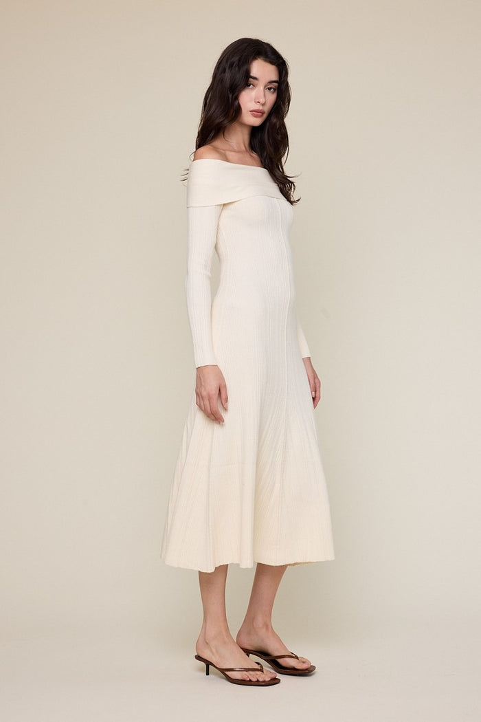 woman wearing a cream off-the-shoulder ribbed midi dress with a flared skirt and heeled sandals