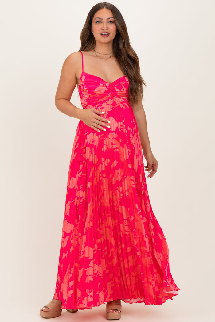 woman wearing a vibrant pink floral maternity maxi dress, showing her baby bump