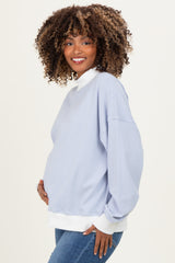 woman wearing a light blue striped maternity pullover with white cuffs and collar, holding her baby bump